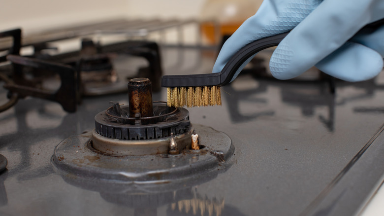 Cleaning stove burner with brush
