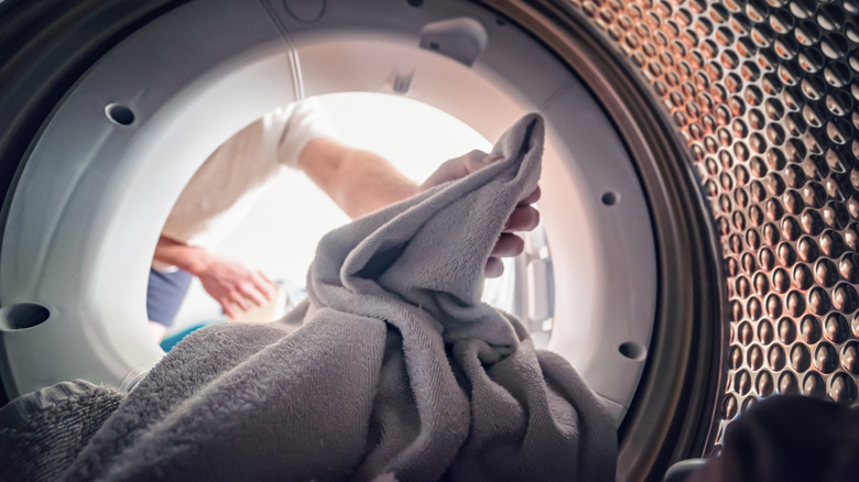 A person loads fabric into a washing machine