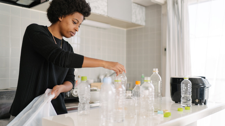 Woman sorting out used plastic bottles in her kitchen