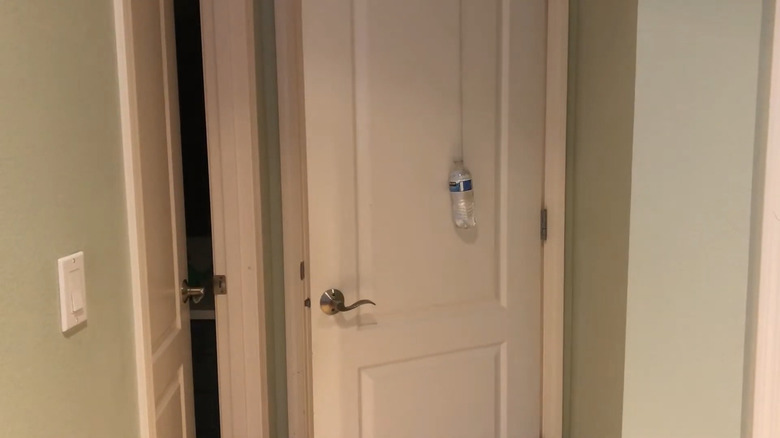 A plastic bottle hanging by a string over a door