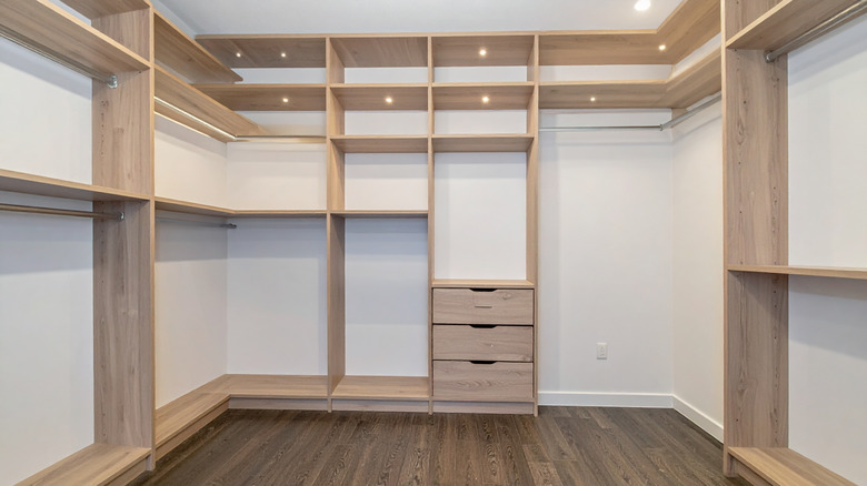 A large, empty walk-in closet with wood shelving