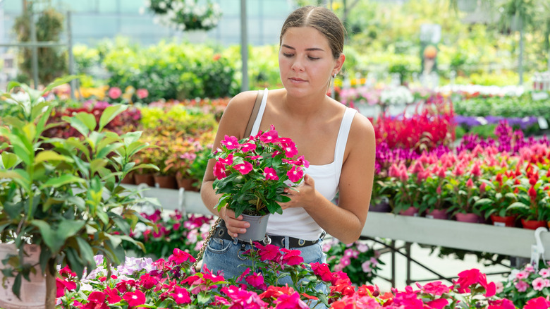 A young woman checks a plant label in a garden store