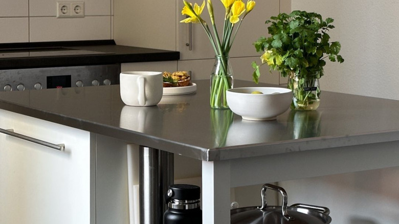 Kitchen with stainless steel island countertop topped with vases and bowls