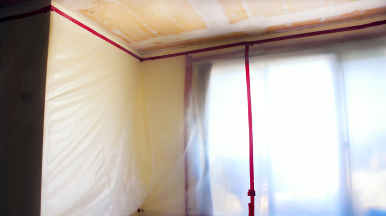 Room covered in plastic with a drywall ceiling
