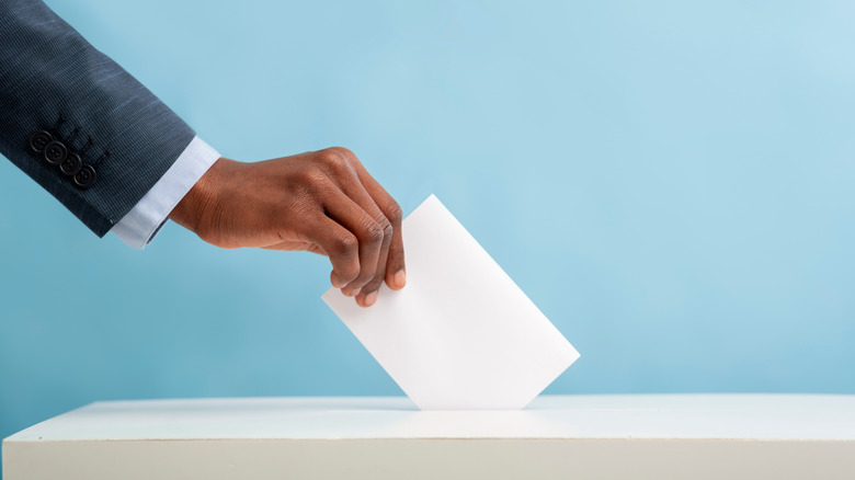 Man placing ballot in box