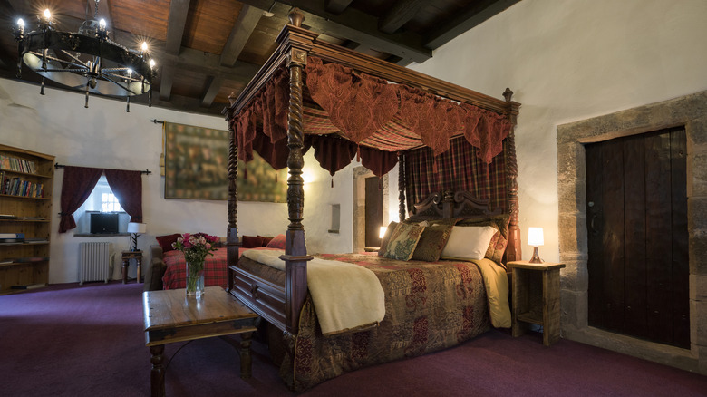Full medieval-style bedroom with four poster canopy bed and dark wood furniture