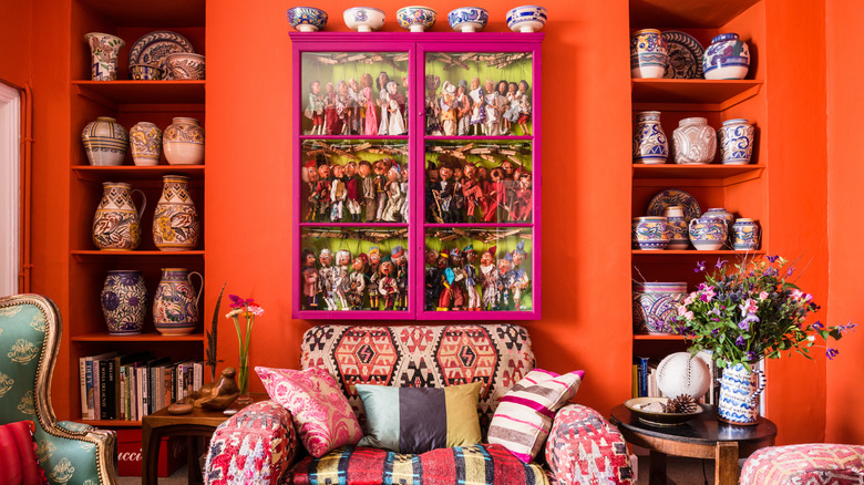 A bright orange and pink living room with large built-ins is elaborately decorated