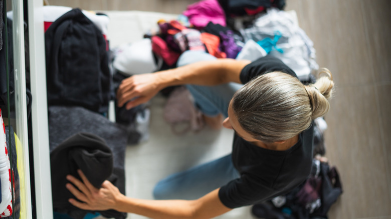 Aerial view of a woman organizing closet, pile of clothes next to her