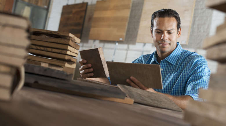 Person holding pieces of reclaimed wood with more piled on the table