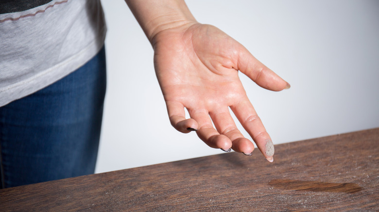 A person displaying their hand after touching a dusty surface