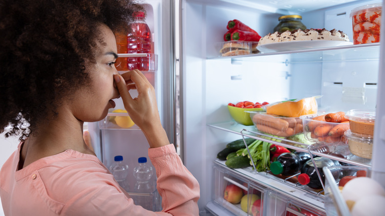 Woman holding nose in fridge