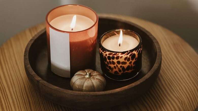 Two candles and a pumpkin figurine on a table