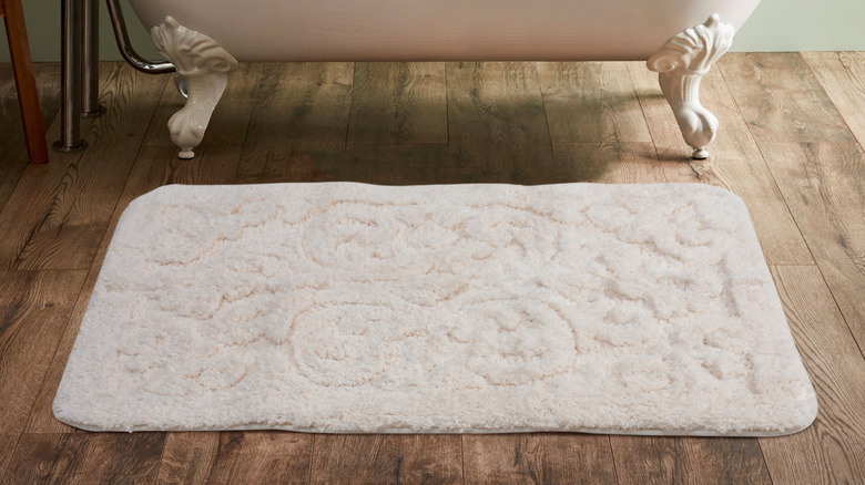 A soft bath mat placed in front of a bathtub in a bathroom