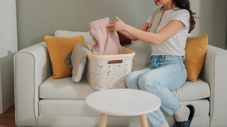 Woman taking out clothes from a white basket