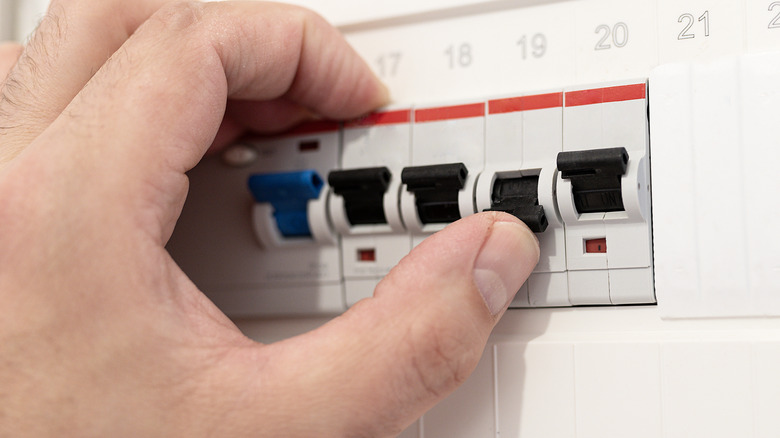 A man resetting a switch in a breaker panel