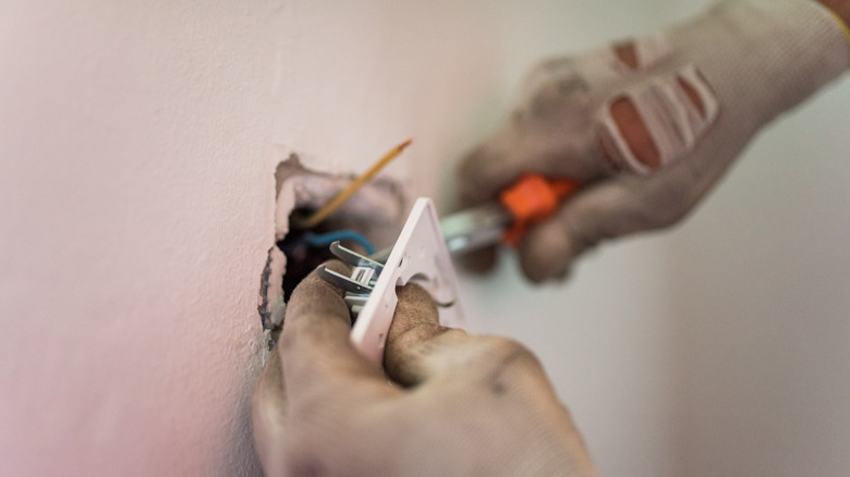 Electrician changing out an old outlet in the wall