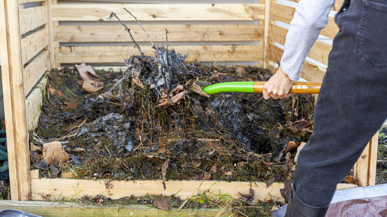 person turning compost pile