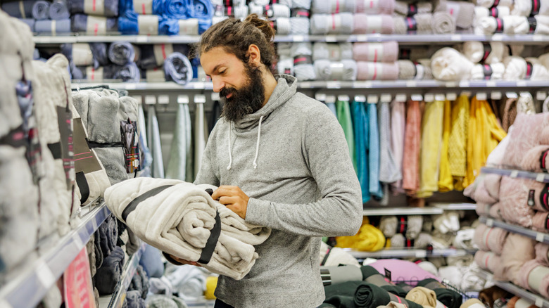 A customer examines a new throw blanket in the linen section of a store.