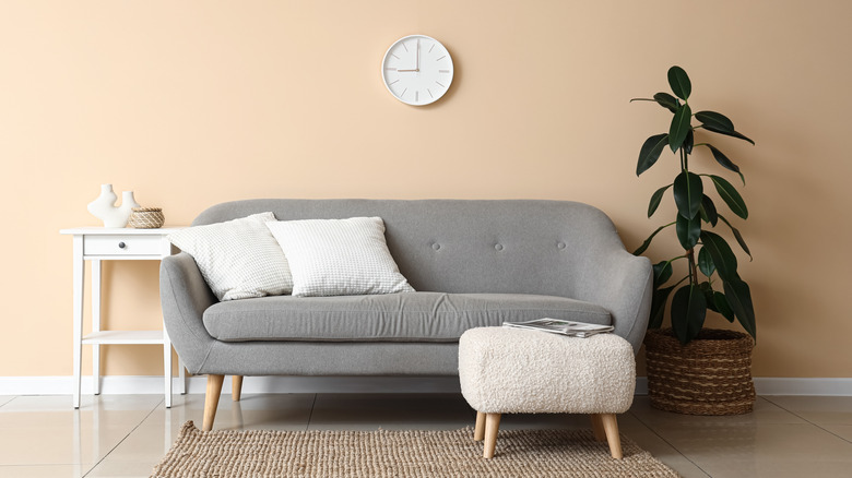 A grey couch with a white shearling ottoman placed in front of it