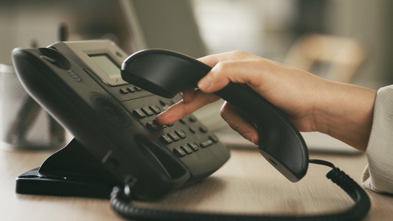 hand pushing buttons on a landline phone