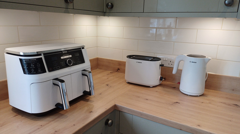 An air fryer, toaster, and kettle on a kitchen countertop