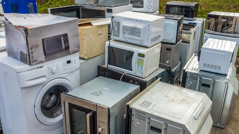 Old microwaves and other appliances stacked outdoors