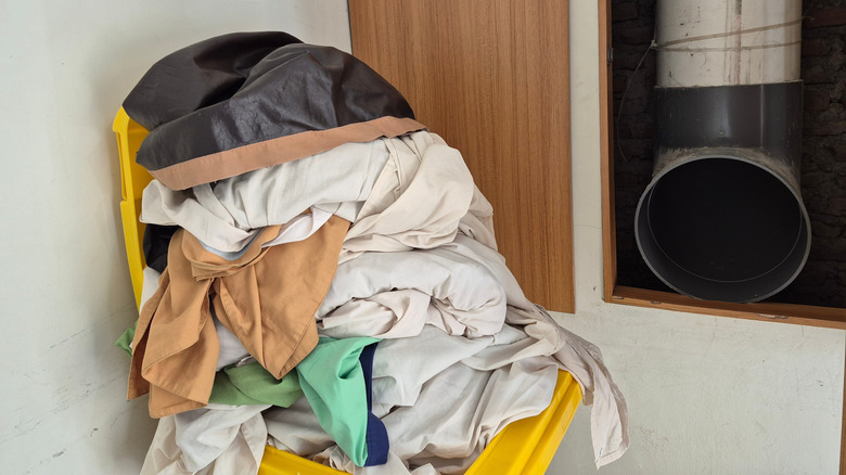 A laundry chute and a pile of dirty laundry.