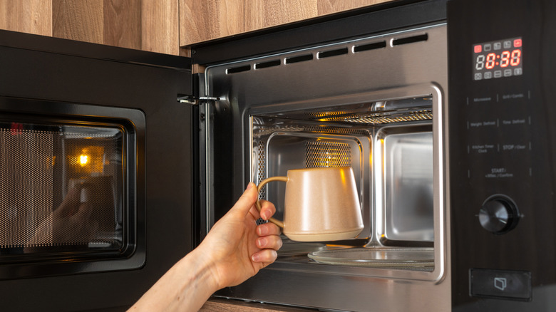 Hand placing cup into microwave