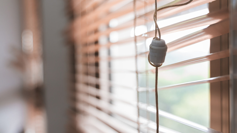 Blinds being pulled down with cord.