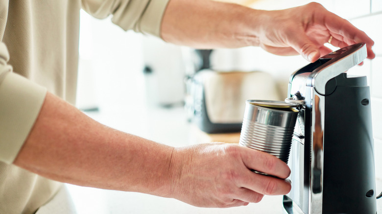 Person using an electric can opener to open can