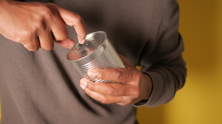 Person using pull tab on can