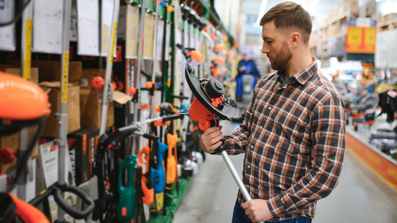 A person looking at electric garden tools in a hardware store