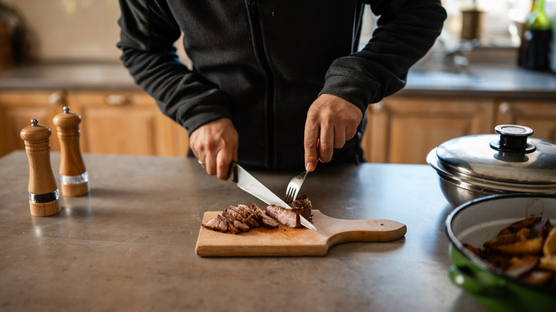 man cutting meat with knife