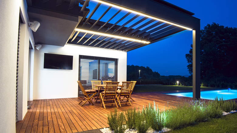 An outdoor TV hanging up over a firepit in front of a seating area