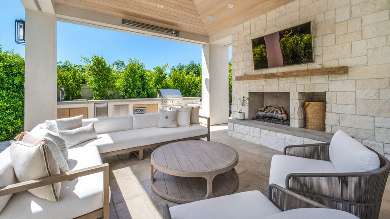 A TV screen mounted onto the wall in front of patio furniture