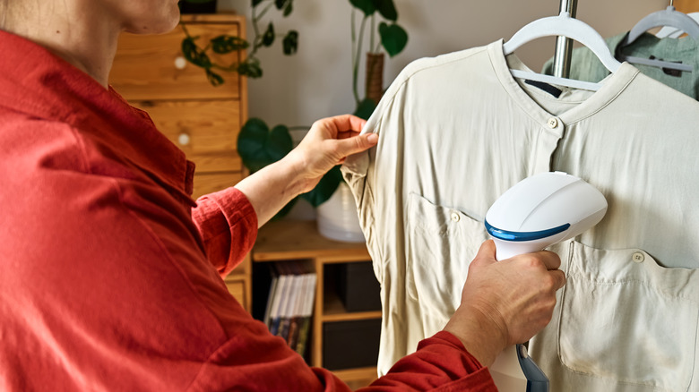 Person using a steamer to remove wrinkles from their clothes