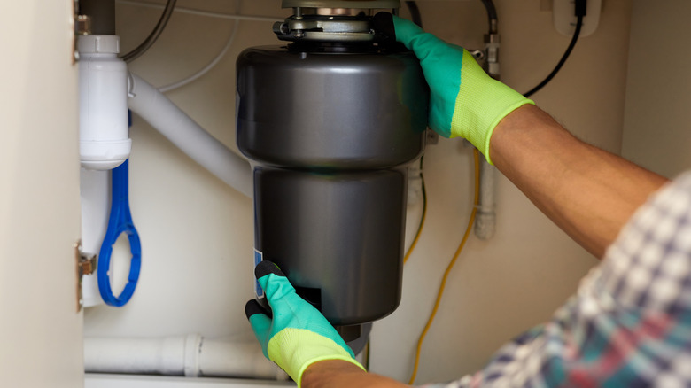 A plumber installing a garbage disposal
