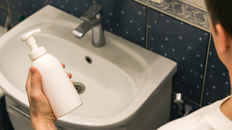 person holding manual soap dispenser