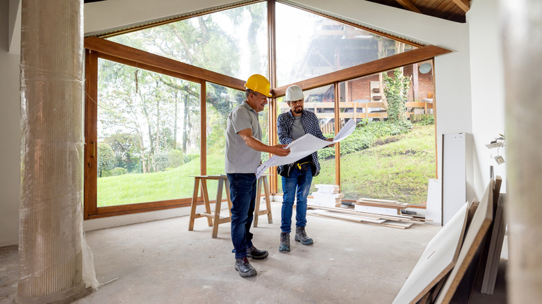 Two people looking at plans while inside a partially constructed or renovated space