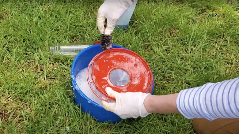hands scrubbing hummingbird feeder