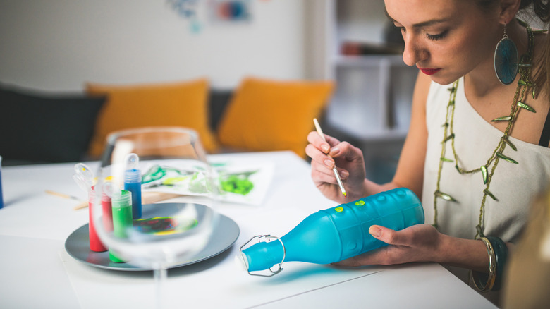 woman painting a glass bottle