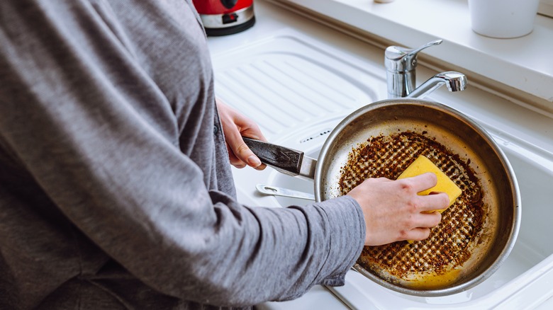 Man holds dirty, oily pan