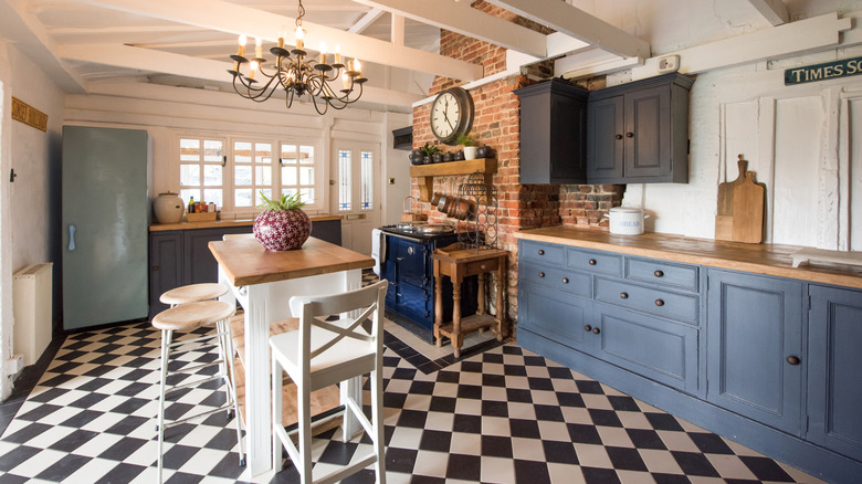 A large country kitchen with blue painted cabinets features a vintage black and white checkered tile floor.