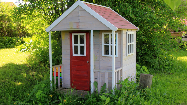 Playhouse surrounded by plants and grass