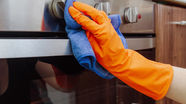 person cleaning oven exterior