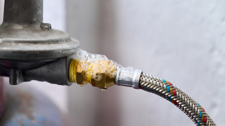 Soapy water bubbling on a gas pipe, indicating a leak
