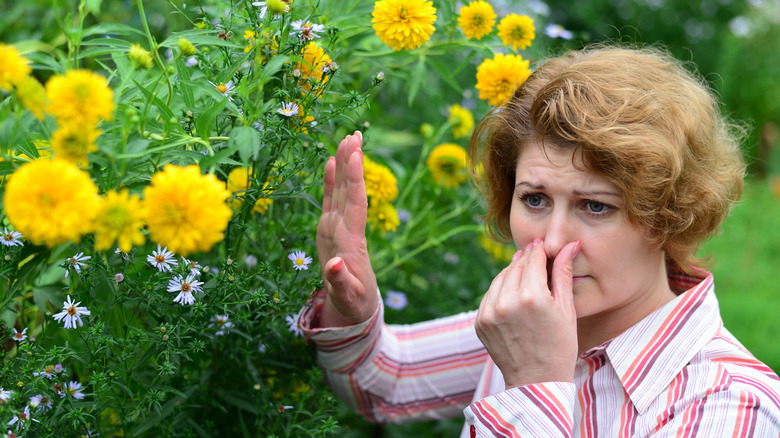 A woman holding her nose in a garden
