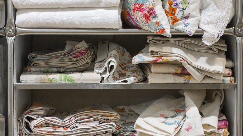 Pile of patterned sheets and pillows on metal shelves