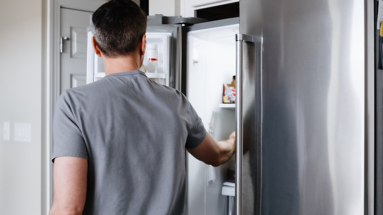 A man is opening up his refrigerator