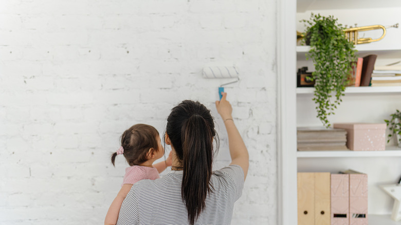 Woman and baby whitewashing bricks